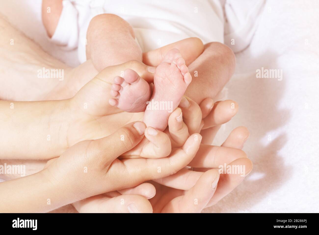 Beaucoup de mains adulte et mère d'enfants avec frère tenir bébé petits pieds de bébé Banque D'Images