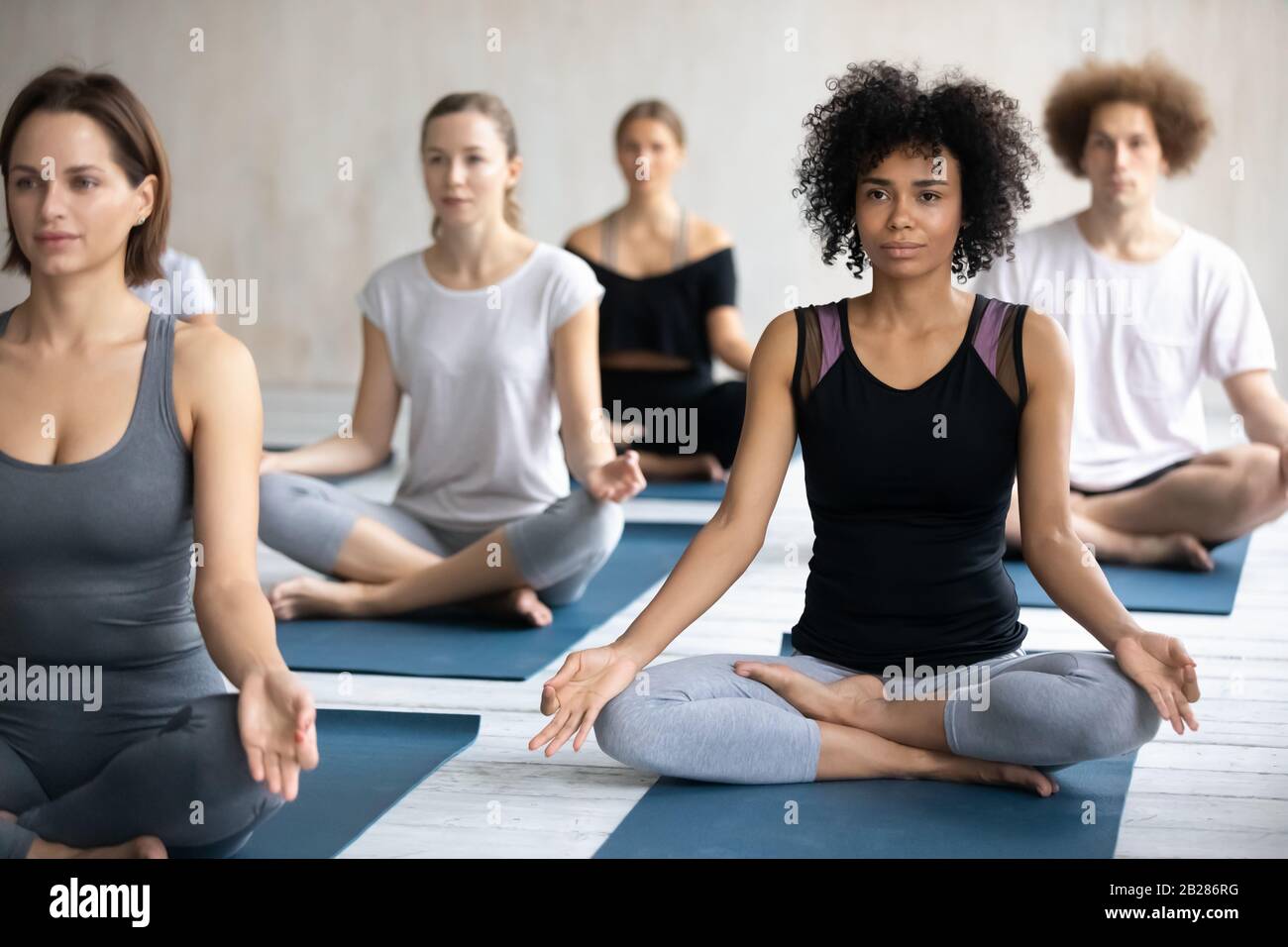 Femme africaine avec groupe de personnes méditant pendant la classe de yoga Banque D'Images