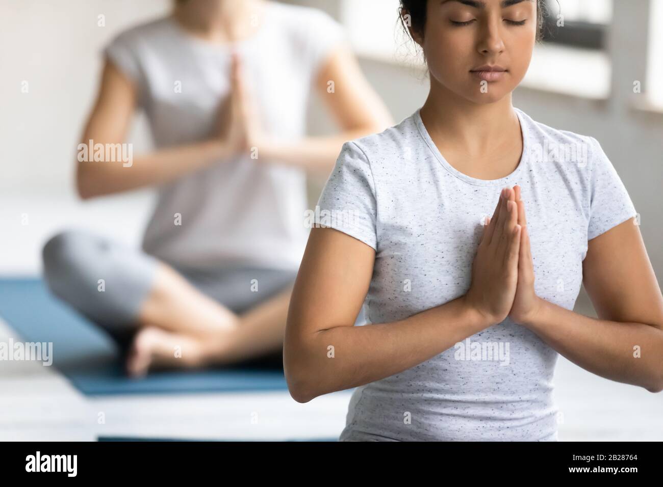 Femme et associés d'origine ethnique indienne méditant pendant la classe de yoga Banque D'Images