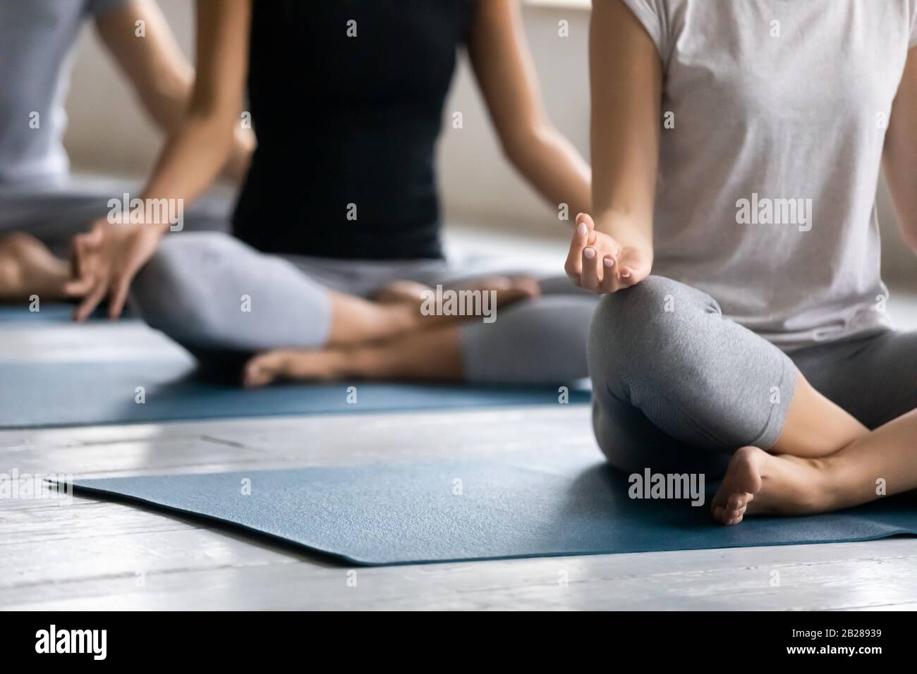 Les personnes assises à pattes croisées pratiquent la méditation à l'intérieur Banque D'Images