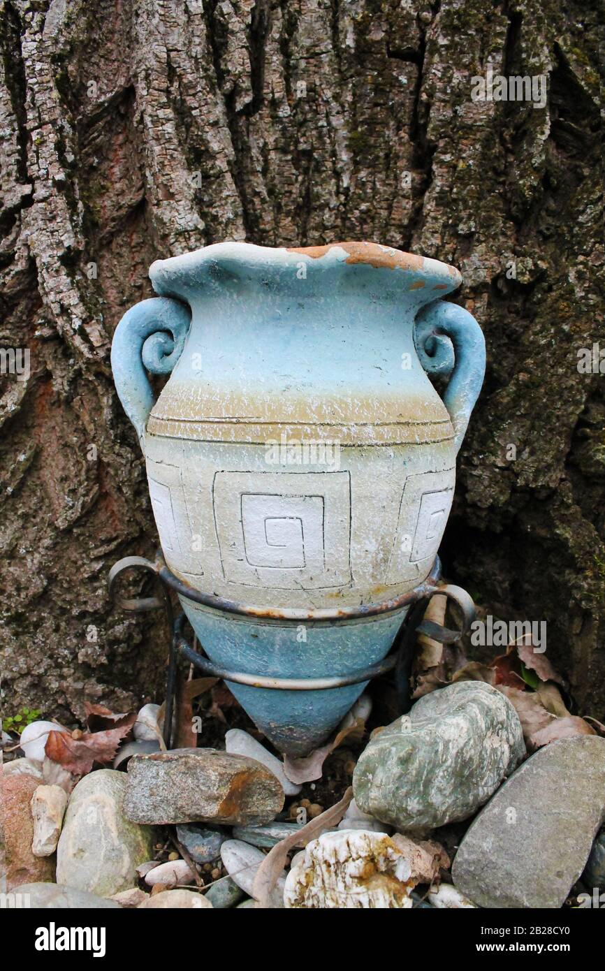 Vase en terre cuite en forme d'amphora avec texture d'arbre comme fond et pierres décoratives en face. Un détail du jardin du monastère Banque D'Images