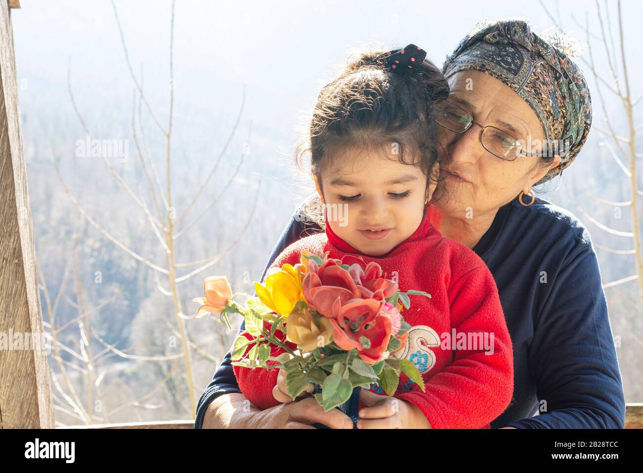 Portrait d'une petite fille tenant un vase de fleur devant le corps avec sa grand-mère musulmane senior, concept de togethness de style de vie Banque D'Images