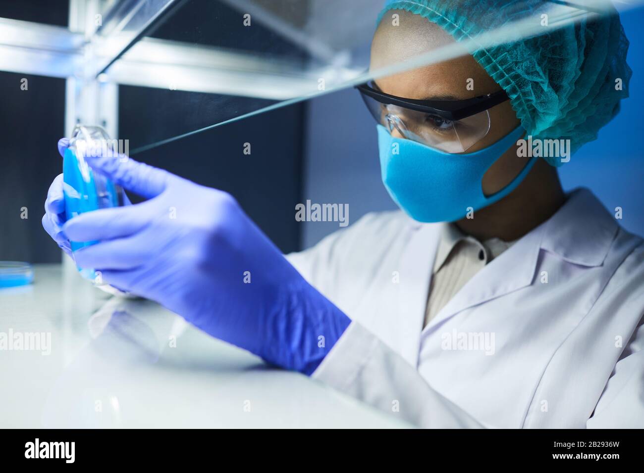 Vue latérale portrait d'une scientifique féminine tenant un plat de Petri tout en travaillant sur la recherche biologique en laboratoire, espace de copie Banque D'Images