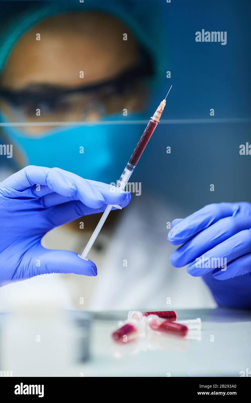 Gros plan sur les femmes scientifiques avec des mains gantées tenant la seringue avec du sang tout en travaillant sur la bio-recherche en laboratoire, espace de copie Banque D'Images