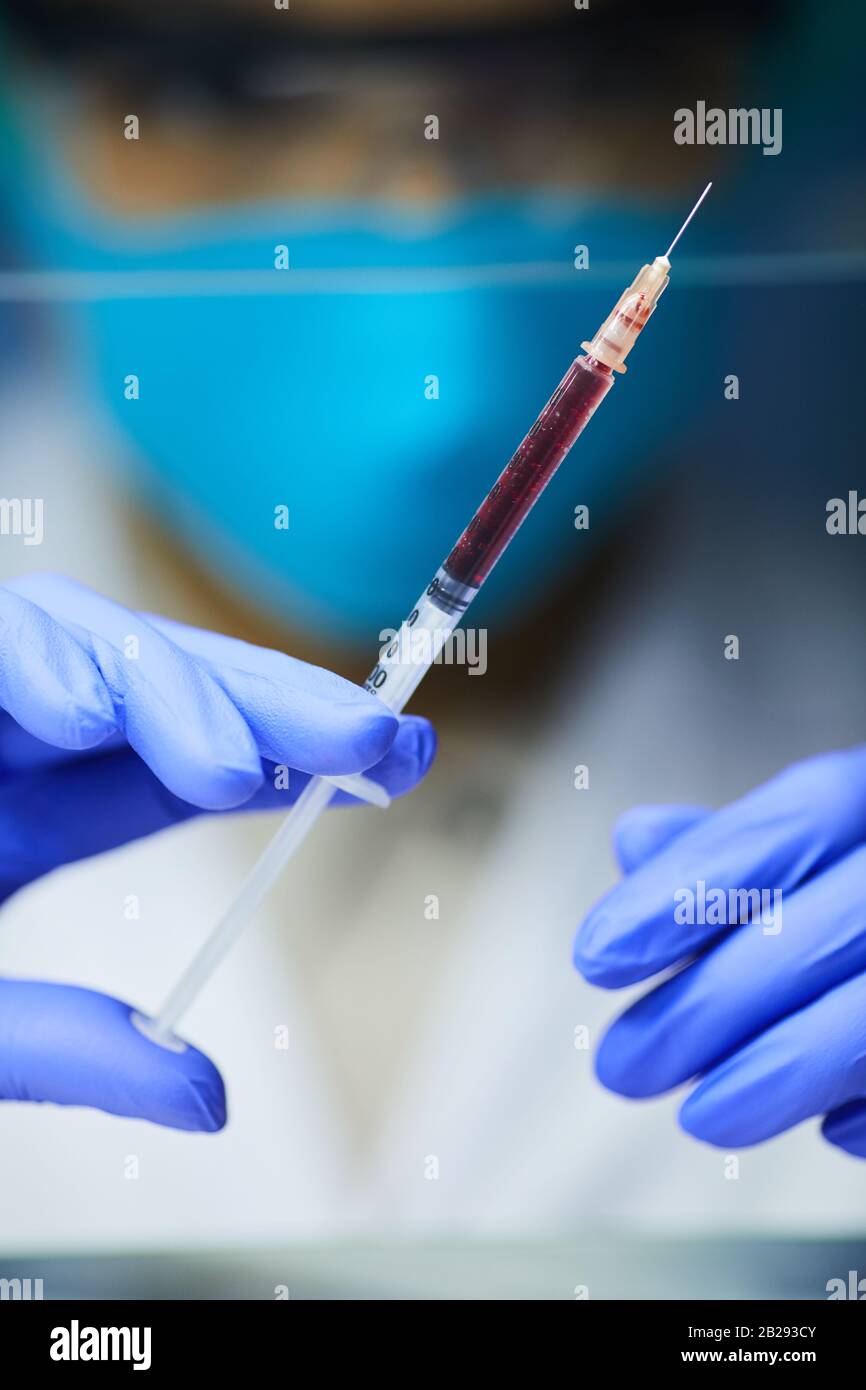 Gros plan de scientifique avec des mains gantées tenant la seringue avec du sang tout en travaillant sur la bio-recherche en laboratoire, espace de copie Banque D'Images