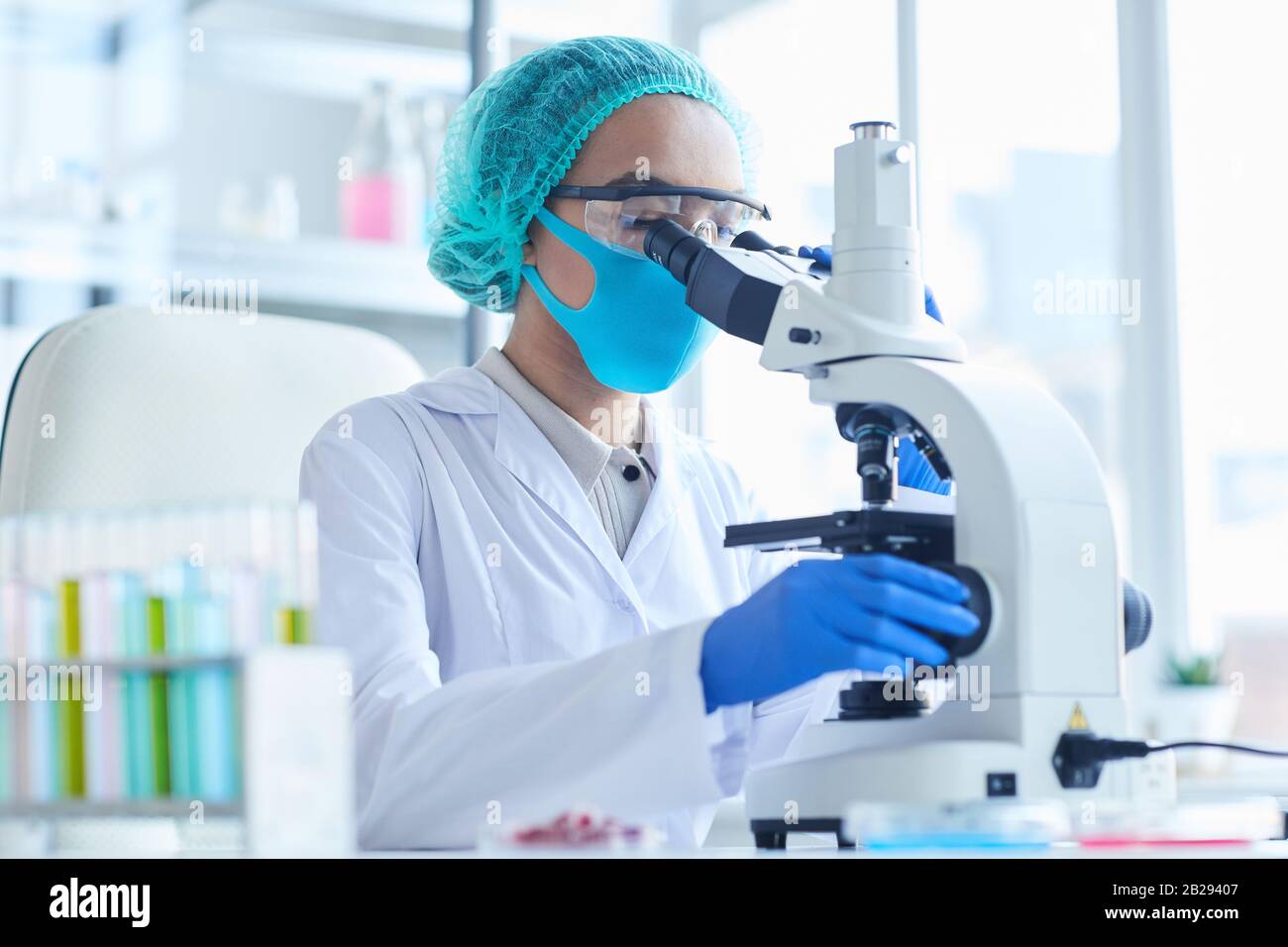 Portrait de la scientifique féminine regardant au microscope tout en travaillant sur la recherche en laboratoire médical, espace de copie Banque D'Images