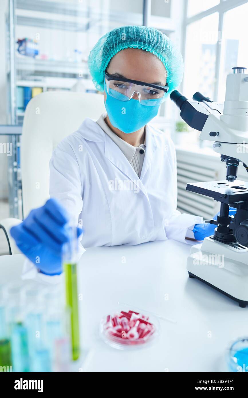 Portrait vertical de la scientifique féminine portant un équipement de protection complet en laboratoire sur la recherche biologique Banque D'Images