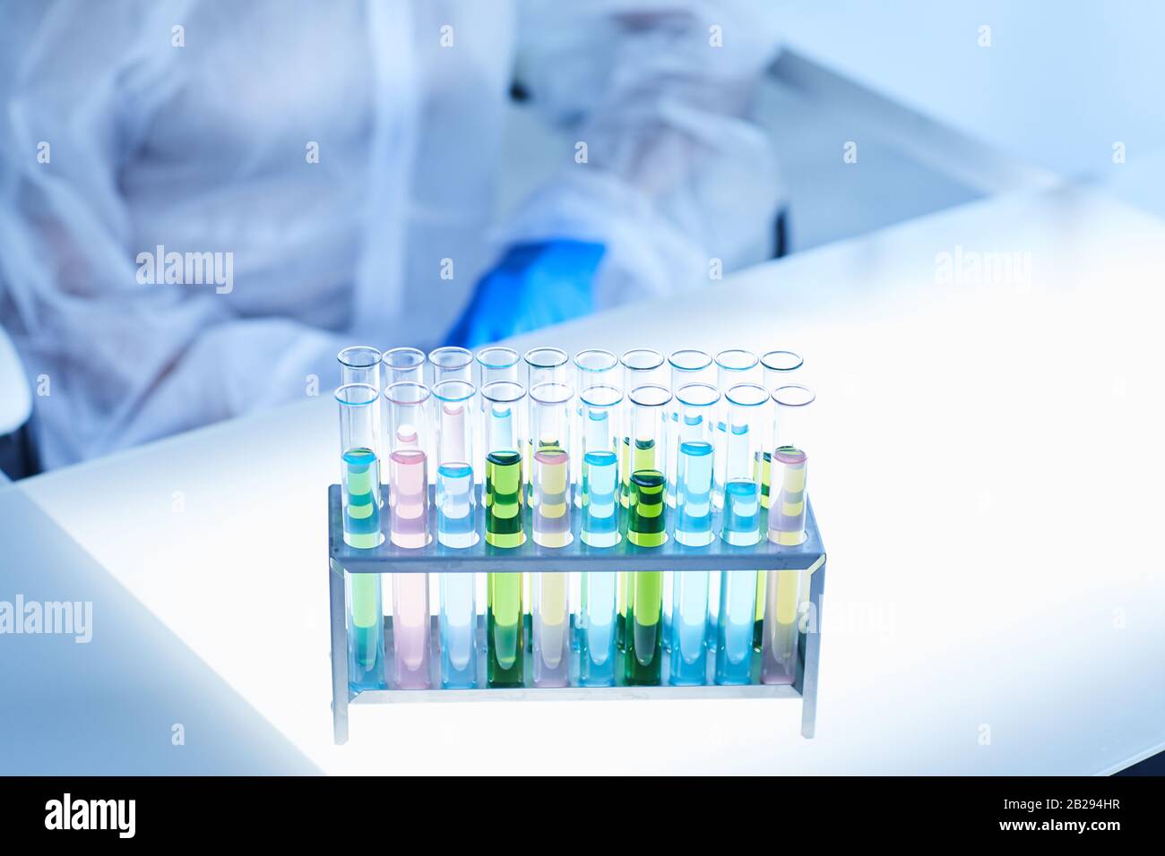 Image d'arrière-plan des tubes à essai avec liquide coloré sur la table dans un laboratoire à lumière bleue, espace de copie Banque D'Images