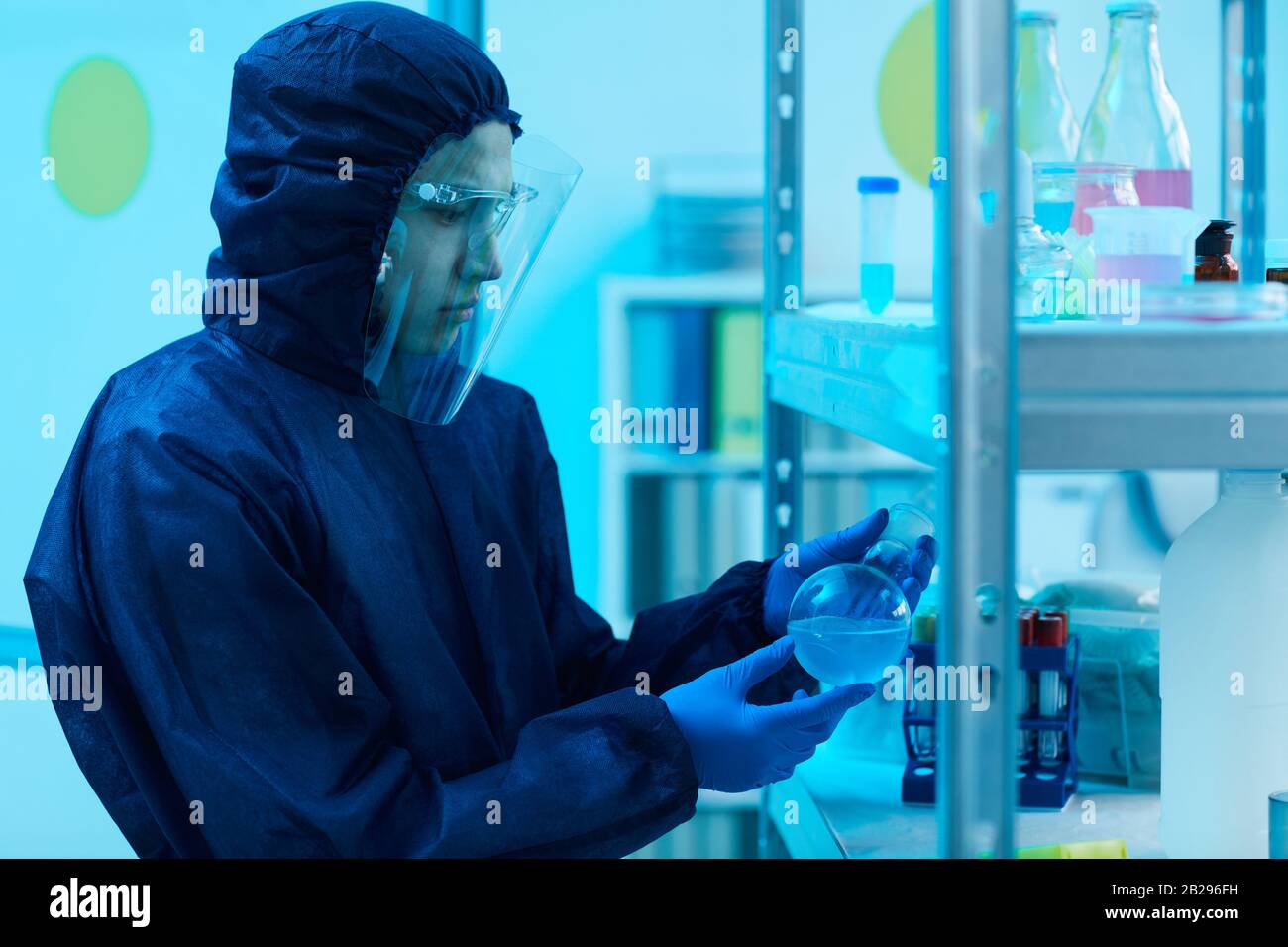 Taille vers le haut portrait d'un scientifique masculin portant un équipement de biodanger examinant les tubes à essai tout en travaillant sur la recherche en bio-laboratoire, espace de copie Banque D'Images