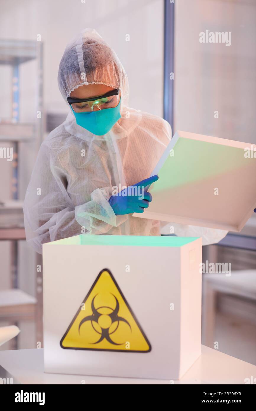 Taille vers le haut portrait d'un scientifique masculin portant une boîte d'ouverture d'équipement à risque biologique avec signe de danger tout en travaillant sur la recherche en bio laboratoire, espace de copie Banque D'Images