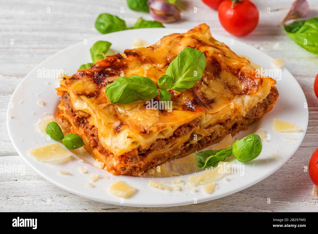Lasagnes de viande au basilic frais et au parmesan dans une assiette sur table en bois blanc. Gros plan. Cuisine italienne. Banque D'Images