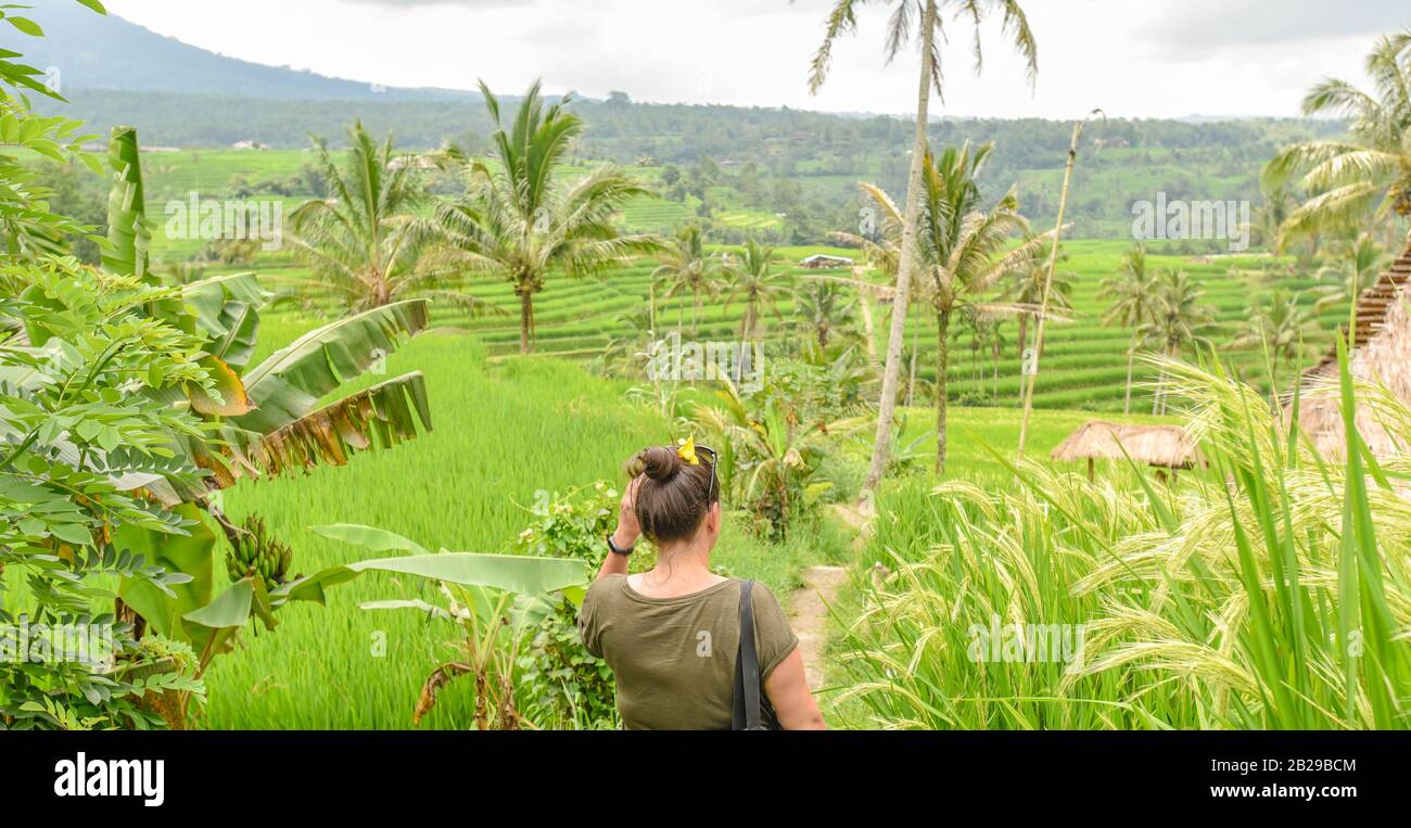 Gros plan de derrière une jeune femme influenceur en ligne debout et posant sur un été nuageux après-midi devant le champ de riz Jatiluwih Banque D'Images