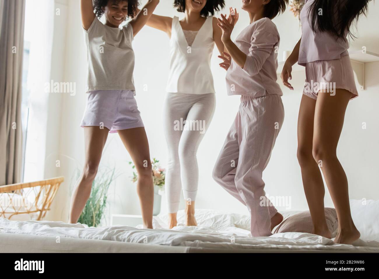 Diverses filles les meilleurs amis portent un pyjama sautant sur le lit Banque D'Images