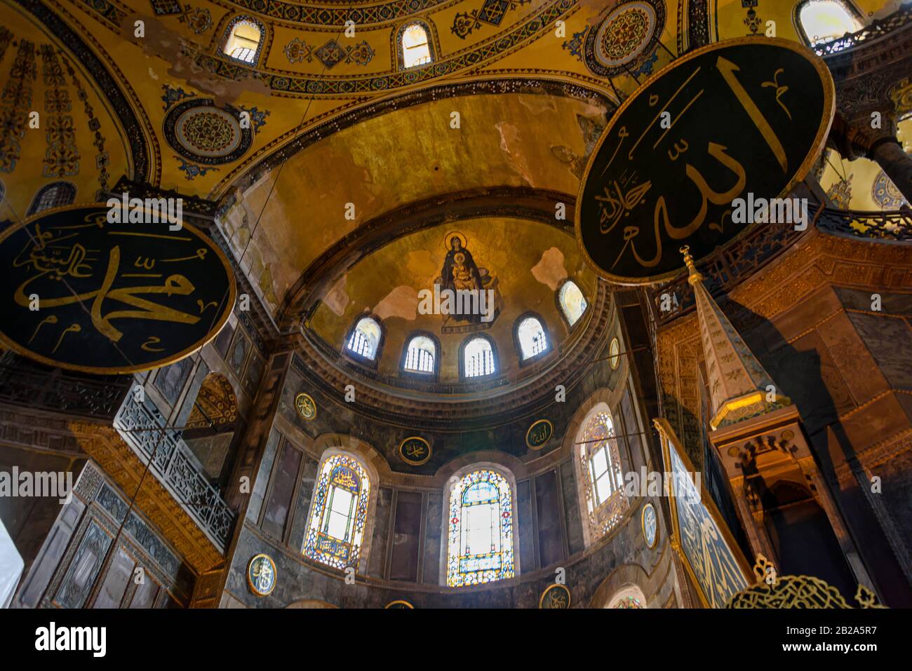 Dôme orné et arches peintes, y compris une représentation de la Vierge Marie avec Jésus, avec des bannières islamiques ajoutées plus tard, à l'intérieur du Musée Hagia Sofia, Banque D'Images