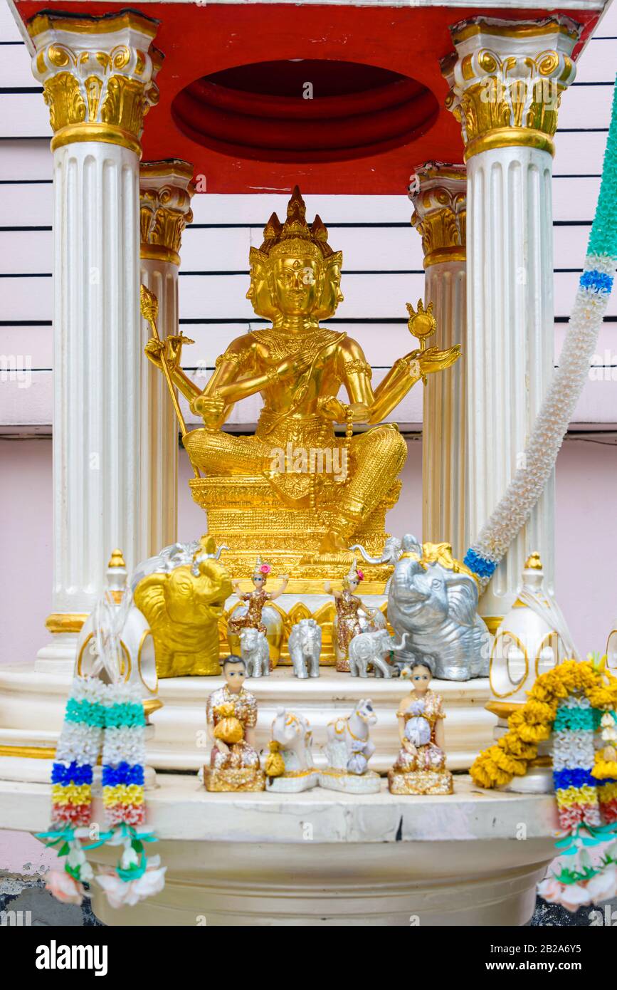 Statue de bouddha d'or à plusieurs facées dans un sanctuaire aux fleurs d'orange, Bangkok, Thaïlande Banque D'Images