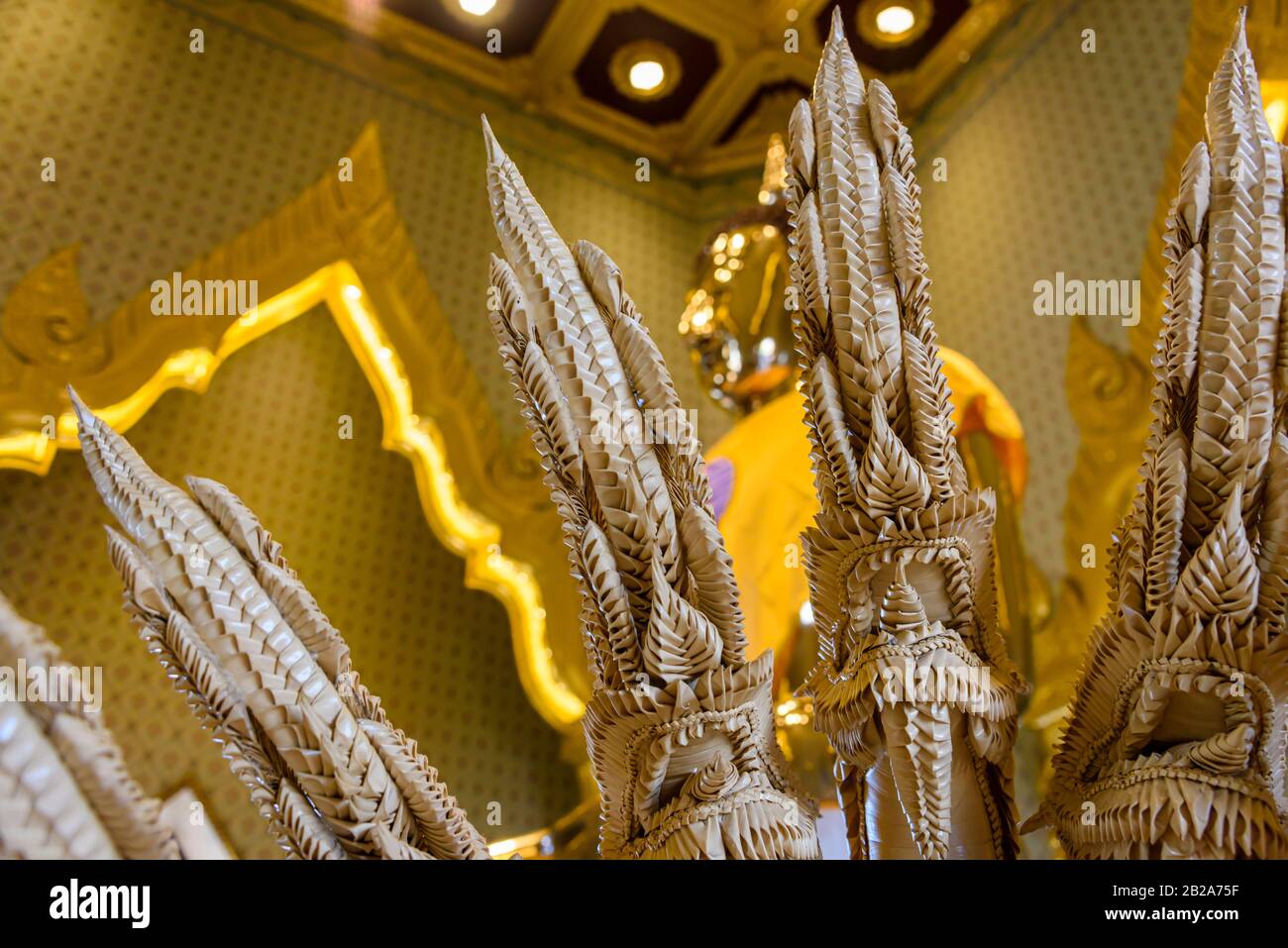 Serpent à plusieurs têtes sculpté en céramique devant une statue dorée de Bouddha avec une robe de safran à l'intérieur du Wat Songkhram, Bangkok, Thaïlande Banque D'Images