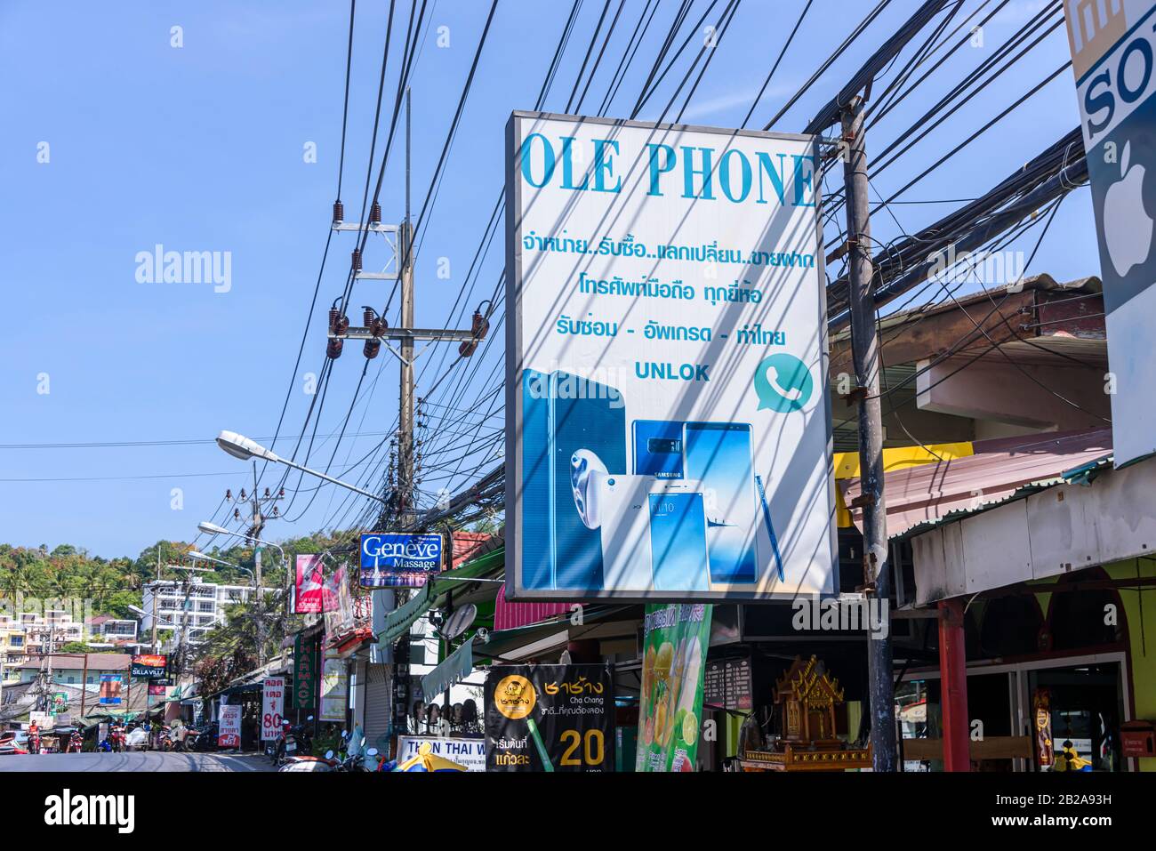 Panneau pour un magasin de réparation de téléphone mobile et de tablette avec des câbles électriques désordonnés et désordonnés accrochés à un poteau d'électricité, Kata, Thaïlande Banque D'Images