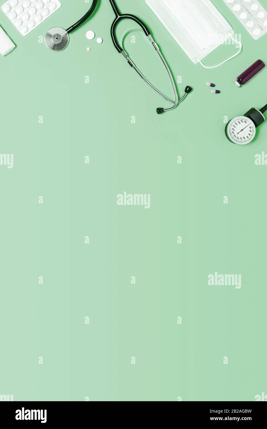 Fond vert menthe médicale avec différents accessoires : stéthoscope, thermomètre, seringue et comprimés. Banque D'Images