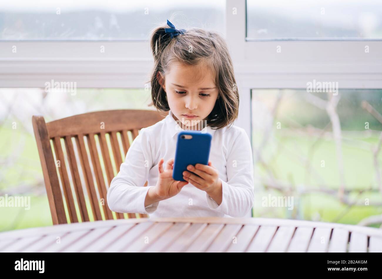 Une petite fille utilise un smartphone de téléphone mobile à la maison Banque D'Images