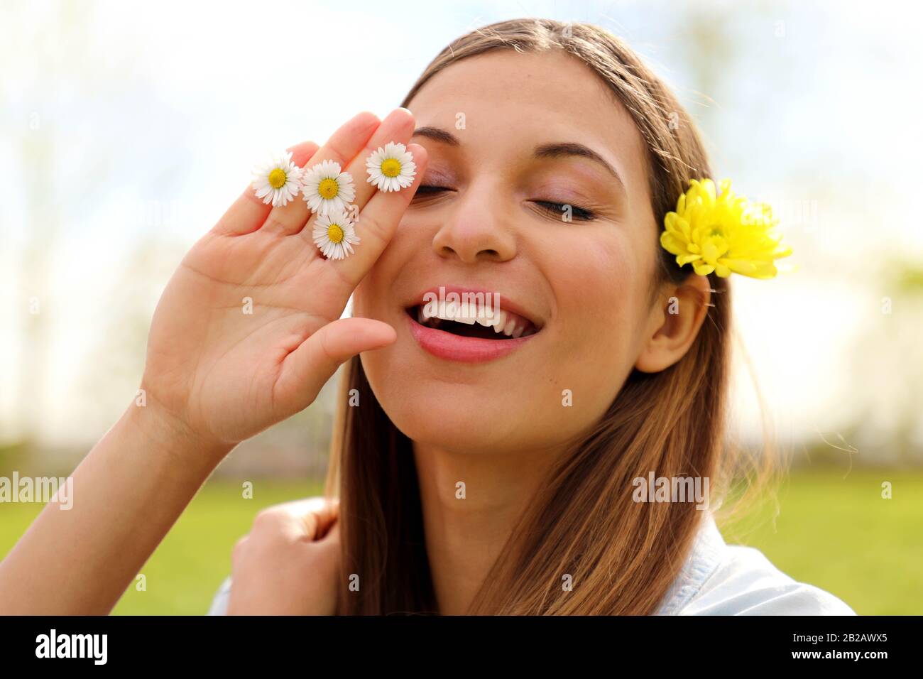 Jolie jeune femme romantique avec fleur sur l'oreille et marguerites entre  les doigts, rester à l'extérieur avec des yeux fermés, gros plan portrait  en printemps Photo Stock - Alamy