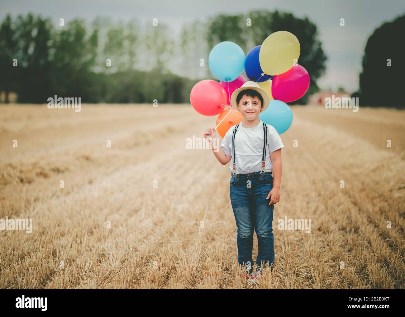 un enfant heureux avec des ballons dans le champ en plein air Banque D'Images