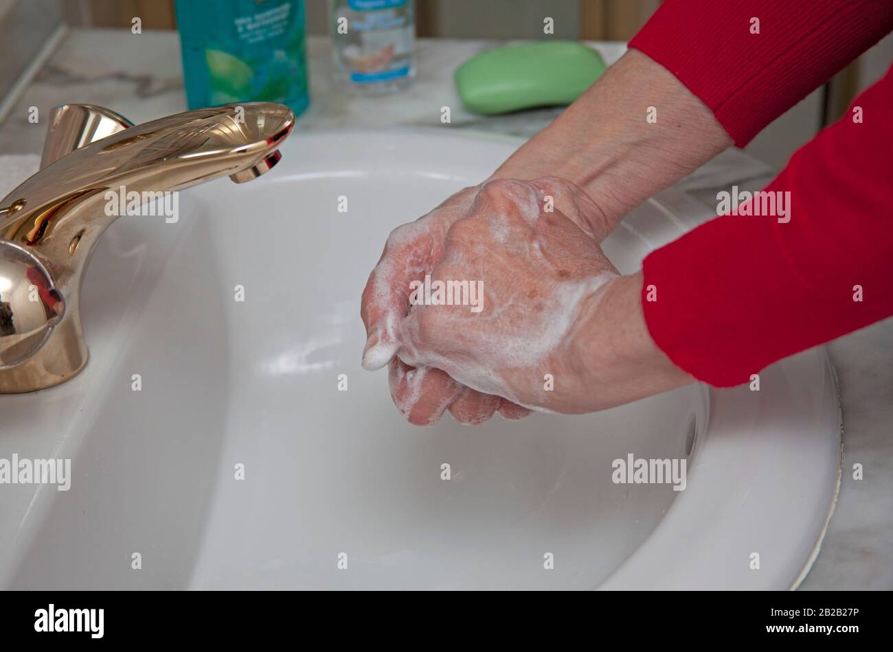 Première affaire de coronavirus confirmée en Écosse. 2 mars 2020. Pour éviter de capturer et de répandre le virus, il est conseillé au public de se laver les mains fréquemment avec du savon et de l'eau ou d'utiliser un gel aseptisant. Photo femme plus âgée se laver les mains dans l'évier de salle de douche. Banque D'Images