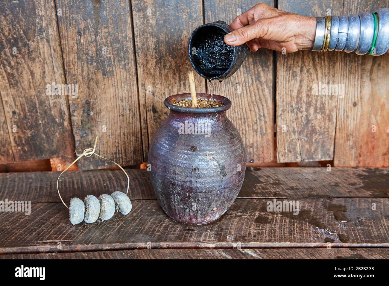 Kayan Lahwi femme ajoutant de l'eau chaude à une liqueur distillée à partir de sorgho fermenté, une boisson très commune parmi les paysans de Kayan. Les billes de levure séchées Banque D'Images