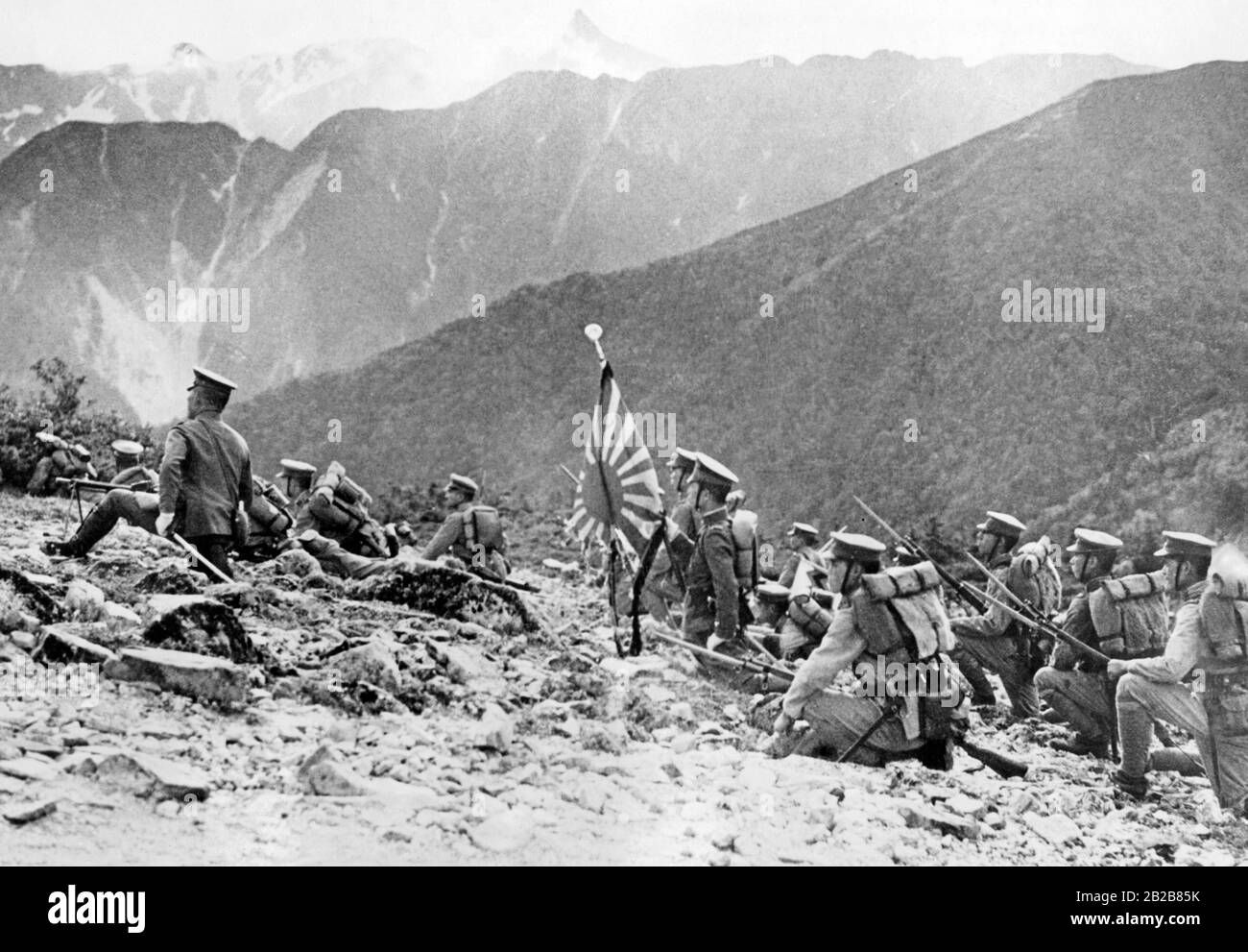 Un groupe de soldats japonais lors d'une manœuvre d'entraînement sur le terrain dans une région montagneuse du Japon. L'un d'eux porte le drapeau de l'armée impériale japonaise. Banque D'Images