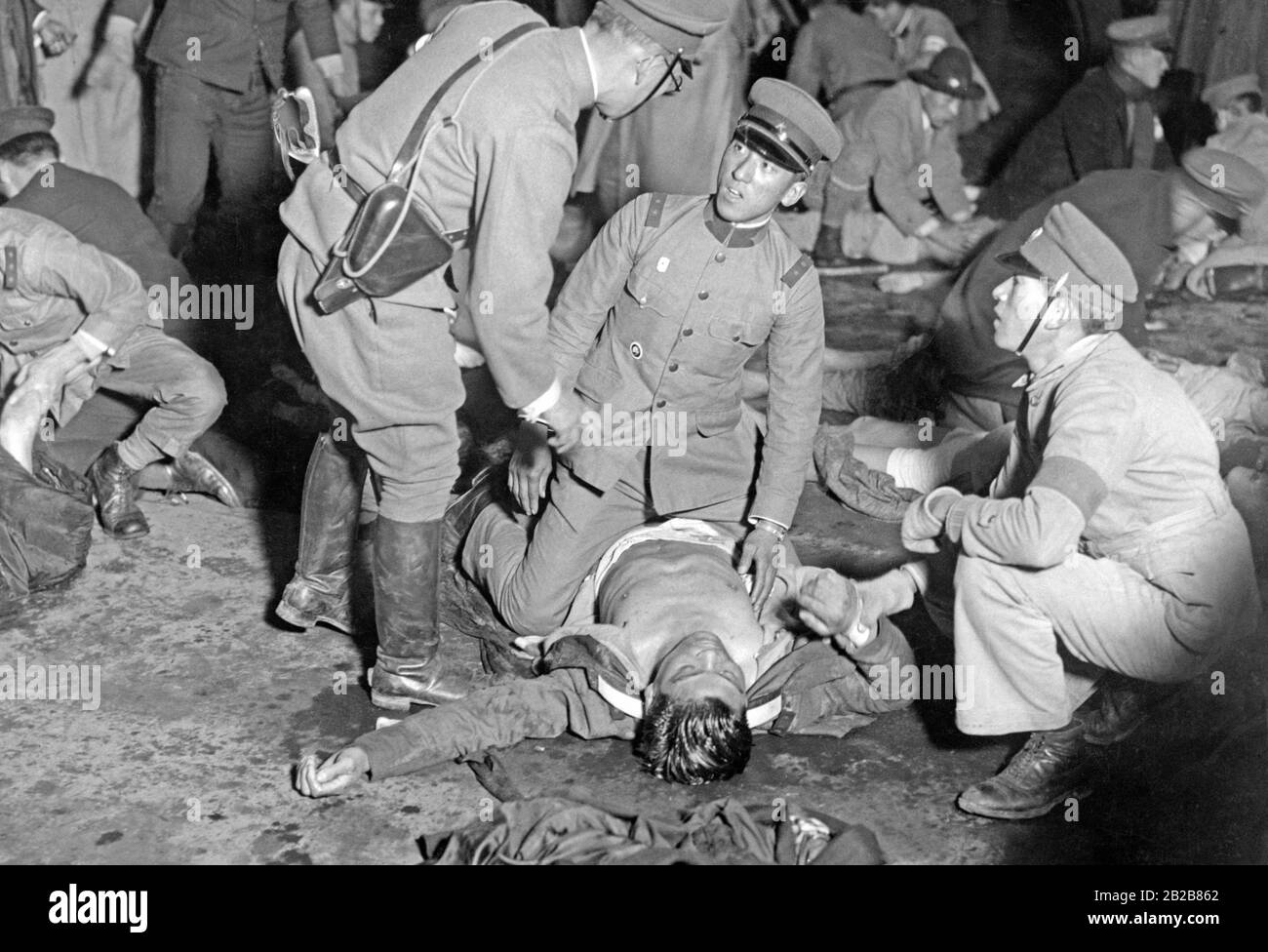 Les blessés sont pris en charge par des policiers dans une rue de Tokyo, après la tentative de coup d'État militaire du 26 février 1936 au Japon. Banque D'Images