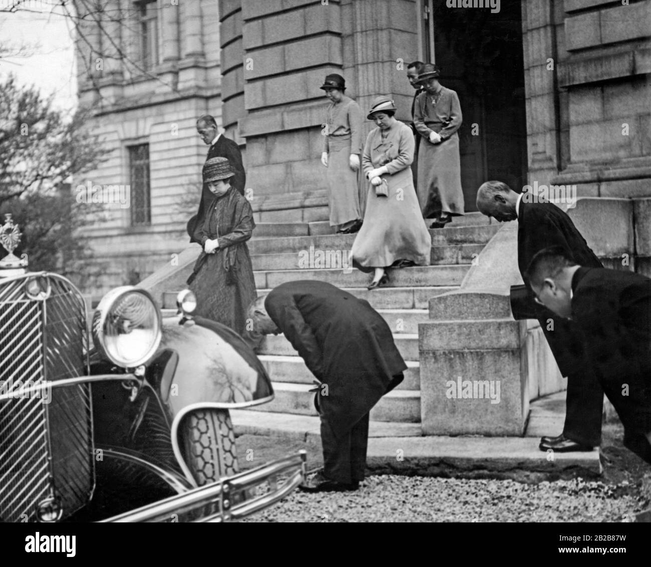 Les membres de la famille impériale japonaise entrent dans une limousine. Leurs serviteurs s'inclinent profondément tout autour. Banque D'Images