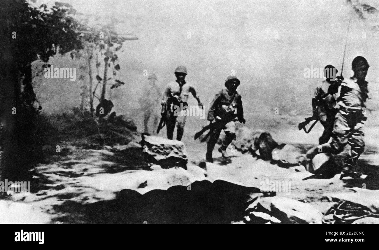 Les soldats japonais chargent sur un terrain pendant une bataille. En face marche un officier avec son épée dessinée. Banque D'Images