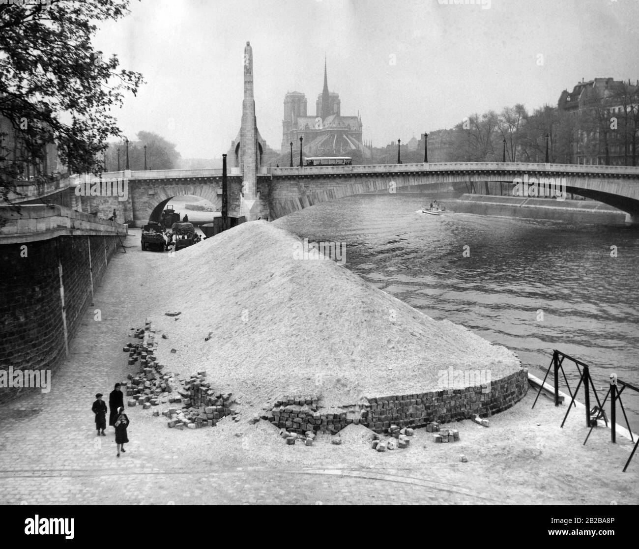 Piles de sable sur les rives de la Seine devant le Pont de la Tournelle à Paris. Derrière le pont se trouve une partie de l'Ile Saint-Louis, en arrière-plan de la cathédrale notre-Dame. Banque D'Images