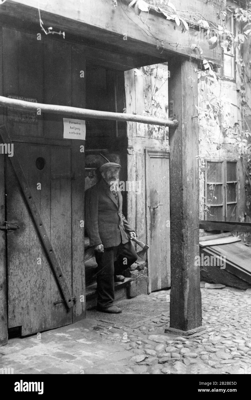 Résident quittant une maison de 100 ans. La photo a été prise peu de temps avant la rénovation. Sur la façade le signe : l'escalier interdit aux étrangers. Banque D'Images