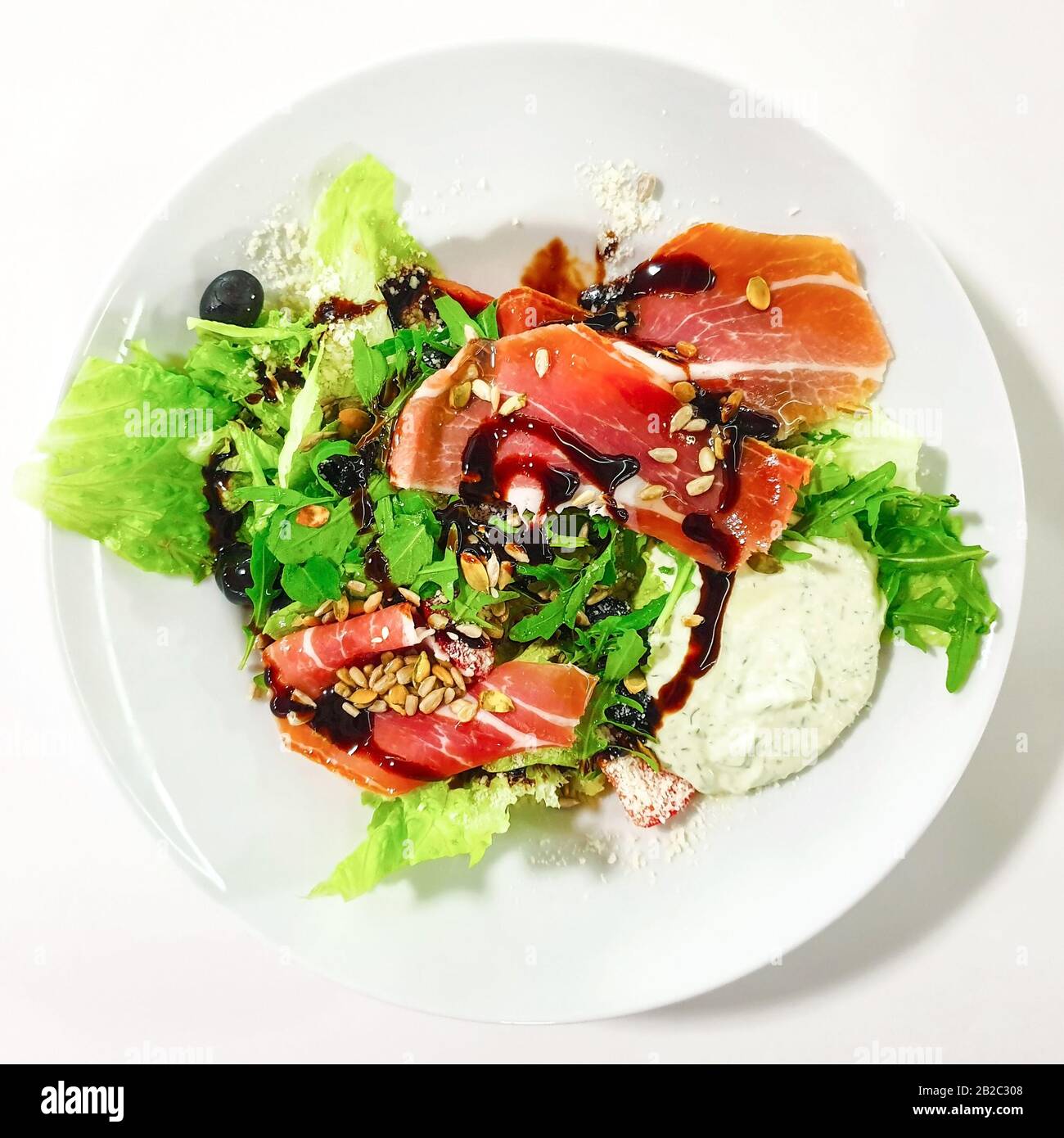 Plaque blanche isolée avec salade de bacon. Banque D'Images