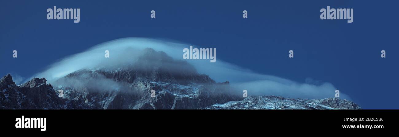 Le sommet de la montagne dans un chapeau du nuage. Montagnes du Caucase. Format de bannière, teinté en bleu Banque D'Images