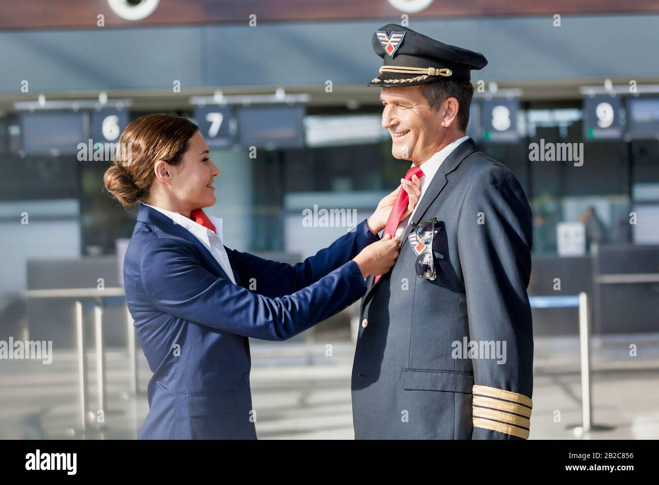 Jeune agent de vol attrayant ajustant la cravate de pilotage à l'aéroport Banque D'Images