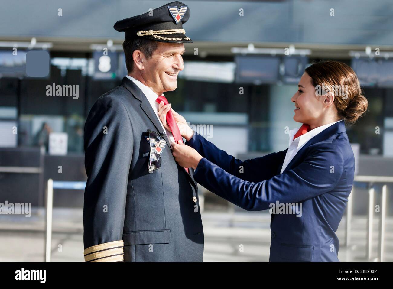 Jeune agent de vol attrayant ajustant la cravate de pilotage à l'aéroport Banque D'Images