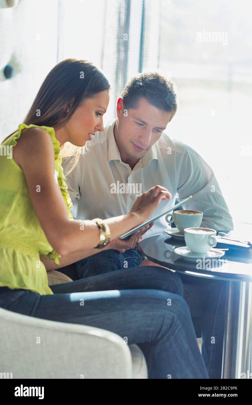 Femme d'affaires discutant de plans sur tablette numérique à l'homme d'affaires tout en s'asseyant et en buvant du café Banque D'Images