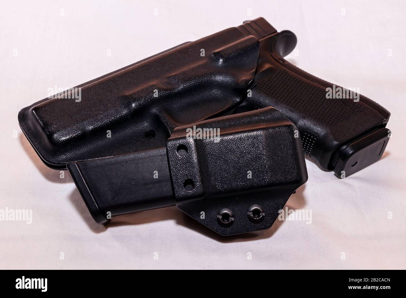 Pistolet noir dans un étui en plastique avec un étui de magasin chargé sur fond blanc Banque D'Images