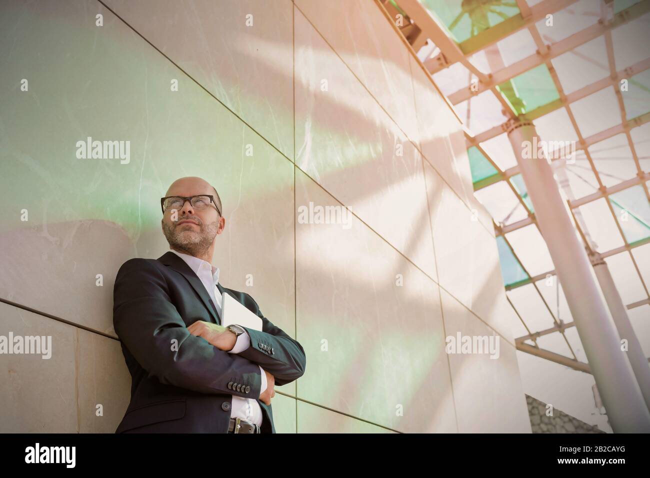 Portrait d'homme d'affaires debout avec les bras croisés tout en se penchant sur le mur Banque D'Images