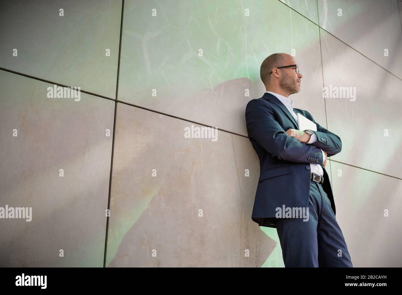 Portrait d'homme d'affaires debout avec les bras croisés tout en se penchant sur le mur Banque D'Images