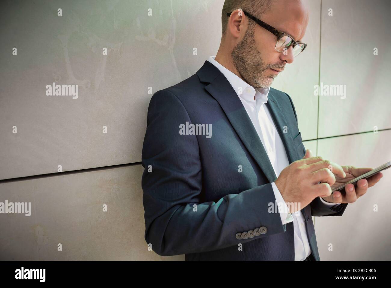 Portrait d'un homme d'affaires utilisant un smartphone tout en se penchant sur le mur Banque D'Images