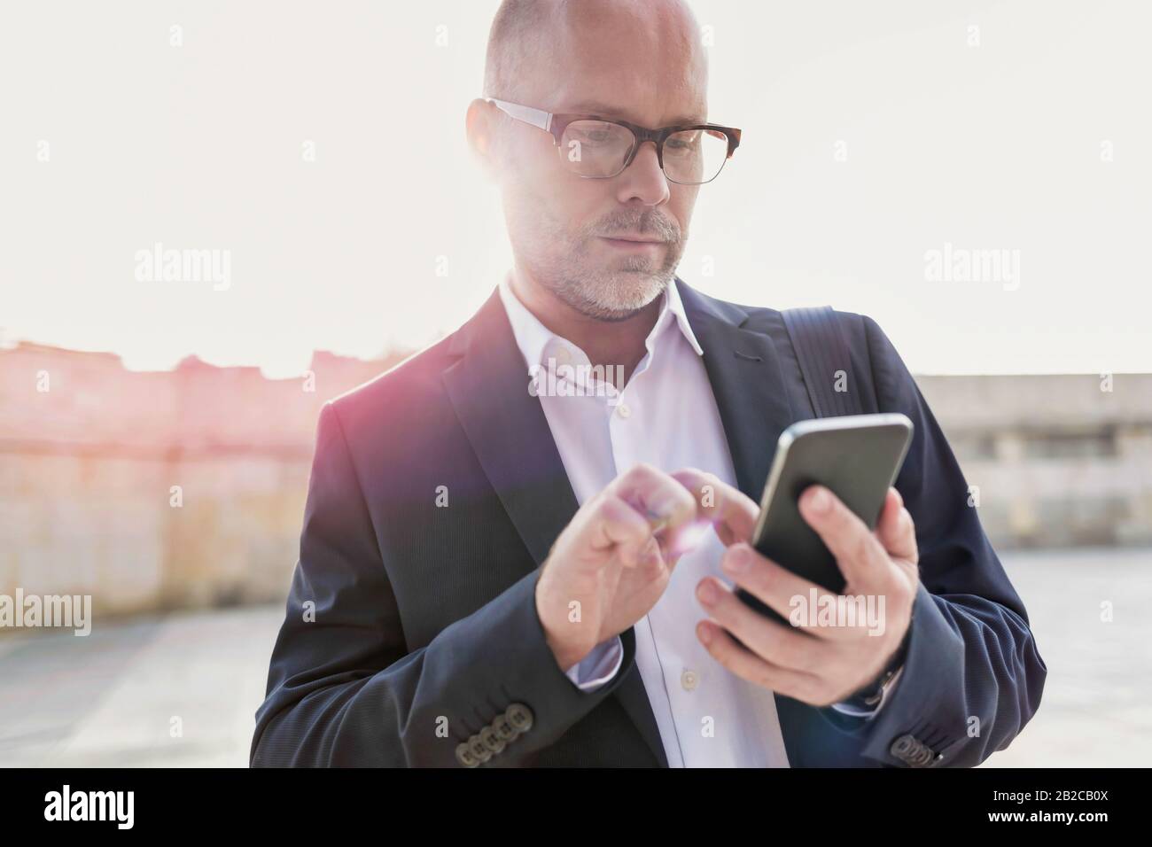 Portrait d'un homme d'affaires utilisant un smartphone tout en se penchant sur le mur Banque D'Images