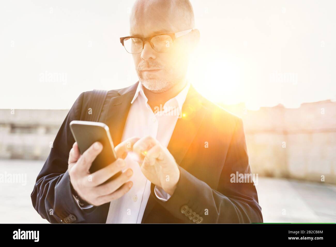 Portrait d'un homme d'affaires utilisant un smartphone tout en se penchant sur le mur Banque D'Images