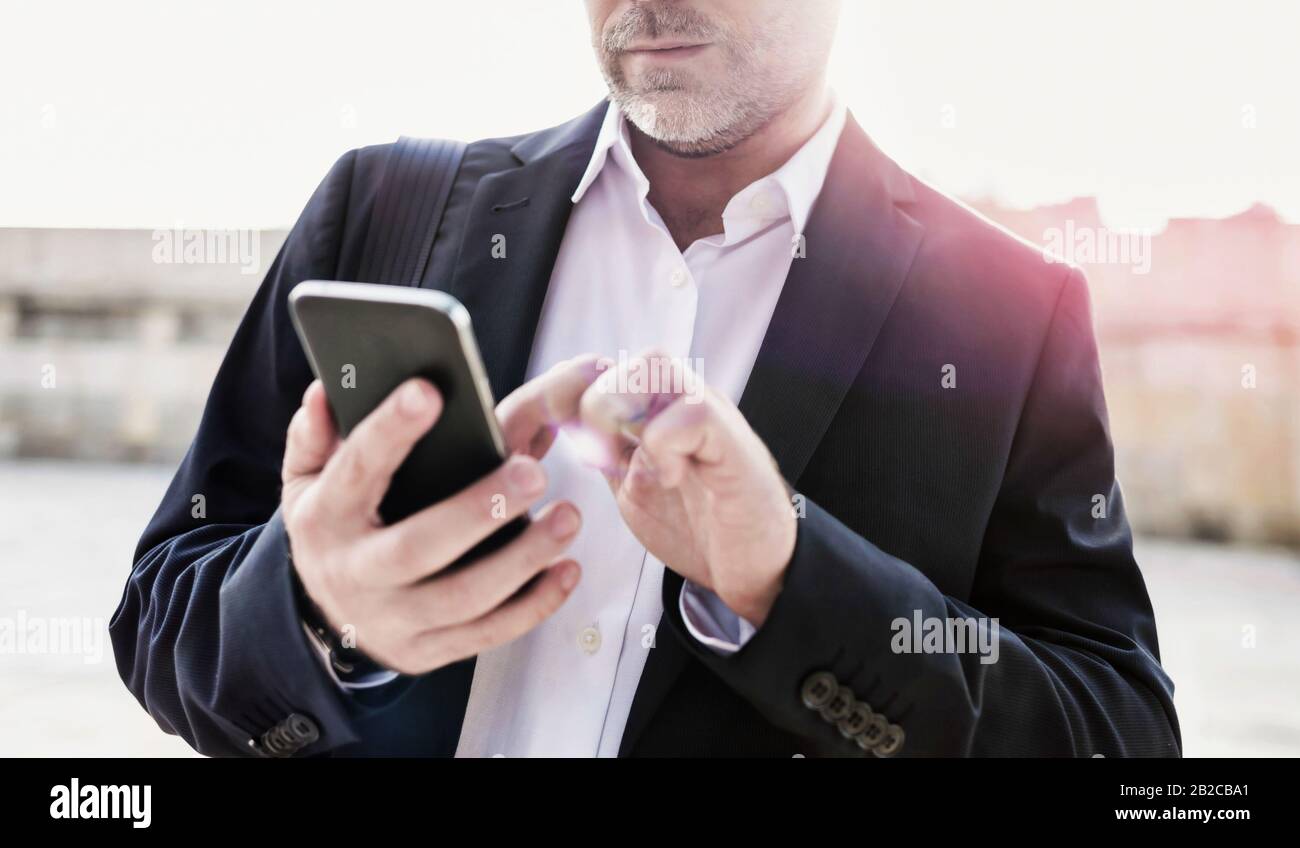 Portrait d'un homme d'affaires utilisant un smartphone tout en se penchant sur le mur Banque D'Images