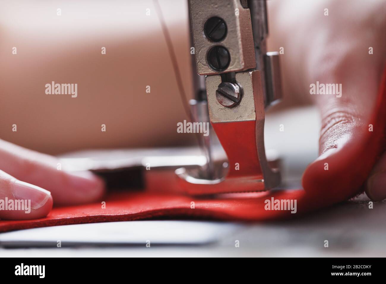 Un artisan en cuir produit des articles en cuir sur une machine à coudre dans sa boutique. Travail à la main. Gros plan. Banque D'Images