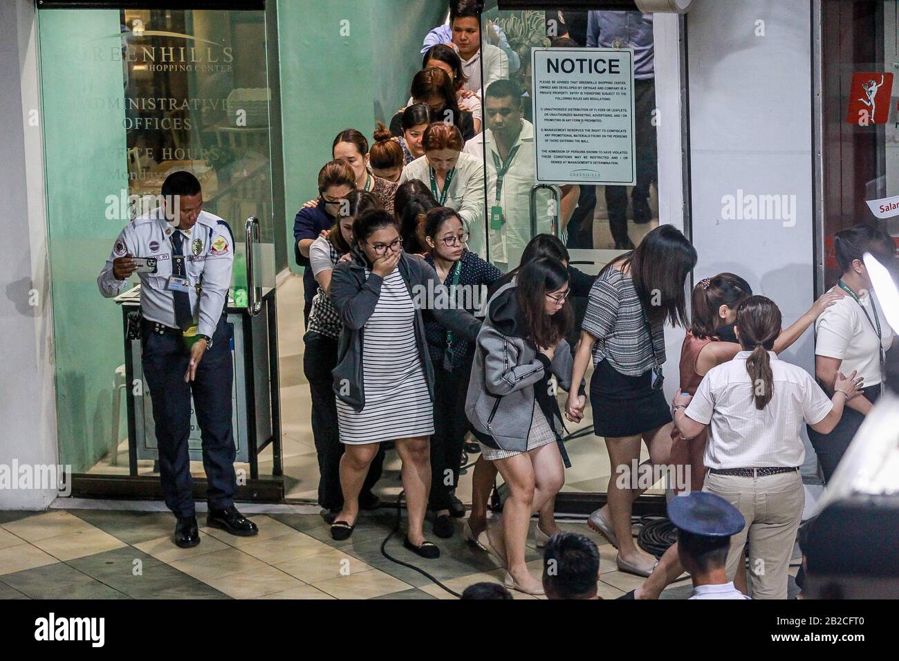 Manille, Metro Manille. 2 mars 2020. Un garde de sécurité conduit les otages à la sécurité, car ils sont libérés lors de la fusillade et de la prise d'otages à San Juan City, dans le métro de Manille, aux Philippines, le 2 mars 2020. La police philippine a mis fin lundi à un otage de 10 heures dans le métro de Manille, convaincant l'homme armé de libérer tous les otages et de se rendre aux autorités. Une trentaine de personnes prises en otage par l'homme armé ont été relâchées et ont quitté le V-Mall dans la ville de San Juan, dans le métro de Manille. Crédit: Rouelle Umali/Xinhua/Alay Live News Banque D'Images