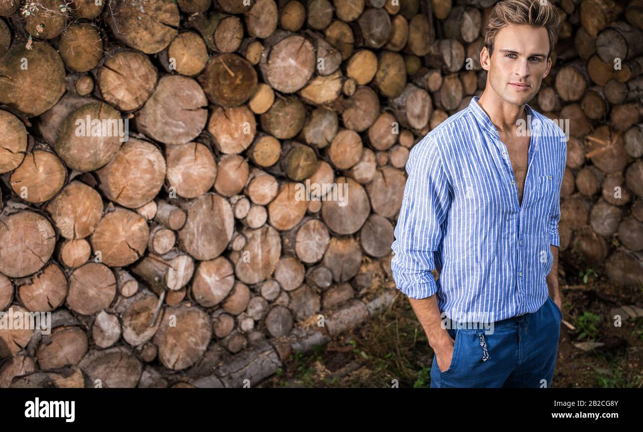 Jeune homme beau dans une chemise décontractée pose près de fond en bois. Banque D'Images