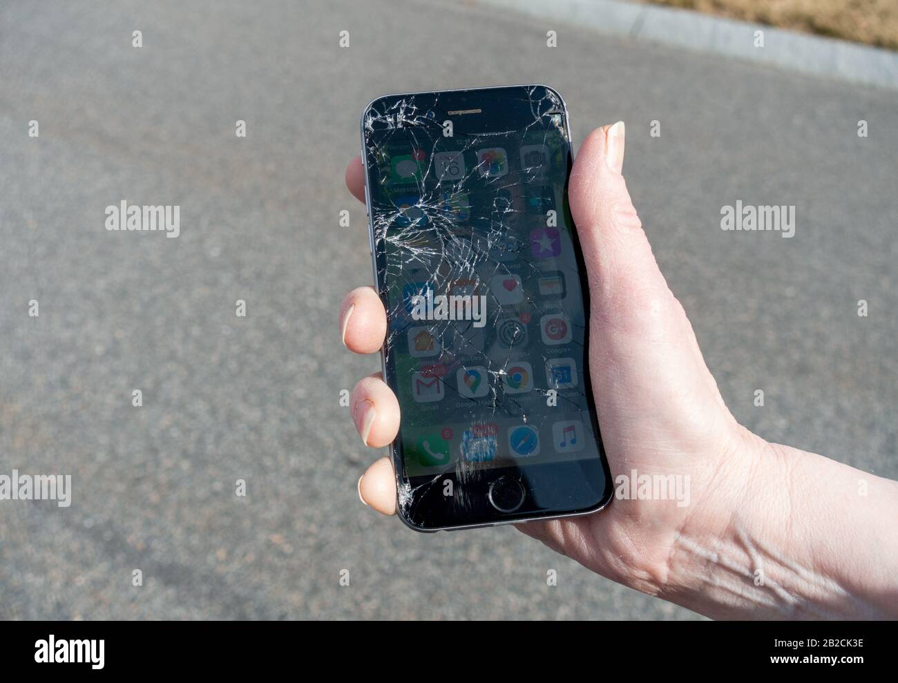 IPhone 6 avec écran en verre brisé qui tombe sur la chaussée d'asphalte Banque D'Images