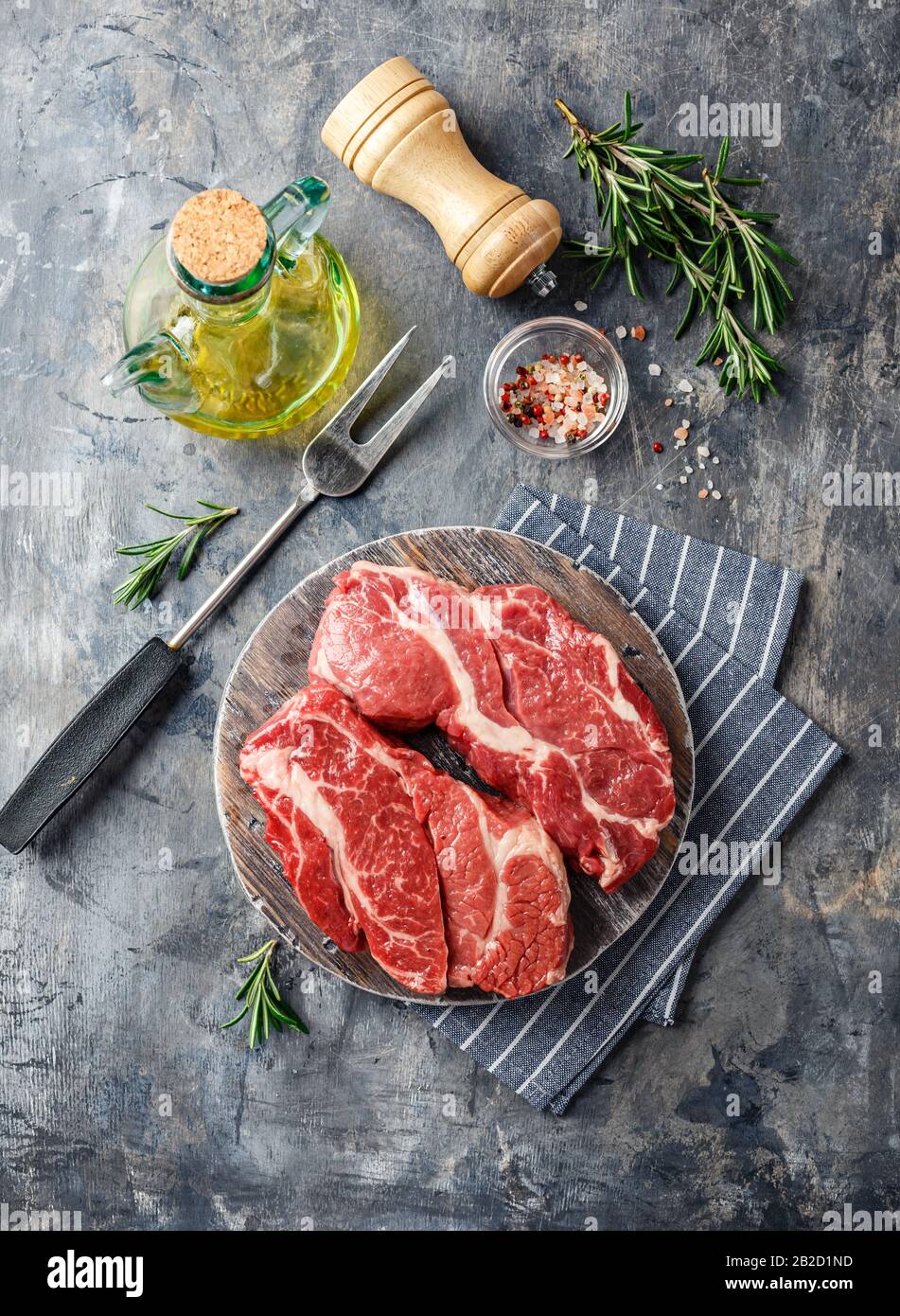 Deux steaks de Chuck Black Angus Chuck roulés à base de viande Brute Fraîche sur un tableau de découpe en bois sur fond gris. Vue de dessus. Banque D'Images